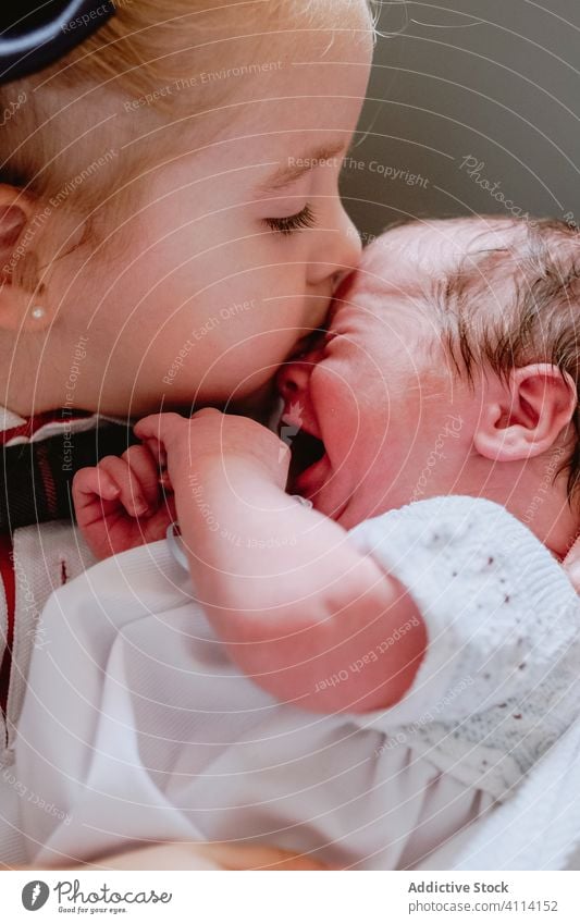 Kleines Mädchen küsst weinendes Baby neugeboren Geschwisterkind Liebe Kuss Schwester Pflege Partnerschaft Zusammensein Umarmen Angebot Umarmung neonatal