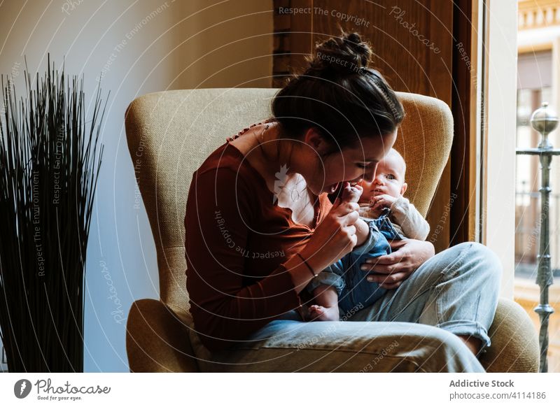 Mutter mit Baby sitzt am Fenster Babysprache sitzen Stuhl heimwärts gemütlich Komfort lässig Glück niedlich Liebe Angebot Frau Säugling bezaubernd Barfuß Kind