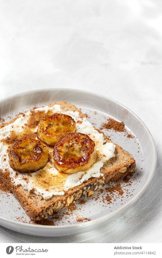 Hausgemachtes getoastetes Brot mit Frischkäse, gebratene Banane, Honig und Lebensmittel Belegtes Brot Zuprosten gebratener Wegerich Liebling Zimt Gesundheit