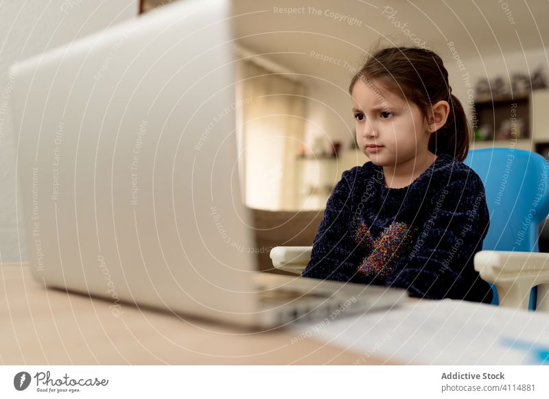 Kleines Mädchen hört dem Lehrer online zu Lektion Laptop lernen zuhören heimwärts abgelegen Aufmerksamkeit Kind Fokus Bildung Gerät Apparatur Tisch niedlich