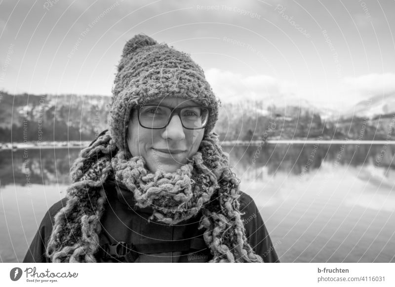 Frau mit Wollmütze und Wollschal vor einem Gebirgssee Portrait Schal Wolle Mütze Winter kalt See Seeufer Porträt Gesicht Erwachsene Bekleidung Alpen Brille