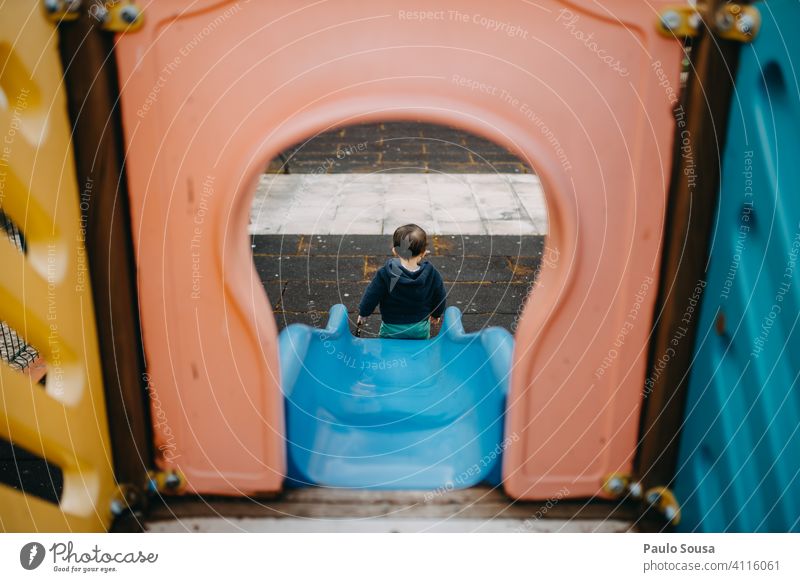 Rückansicht eines auf dem Spielplatz spielenden Kindes 1-3 Jahre Sliden Park Freude Kleinkind Tag Farbfoto Mensch Kindheit Außenaufnahme Spielen farbenfroh