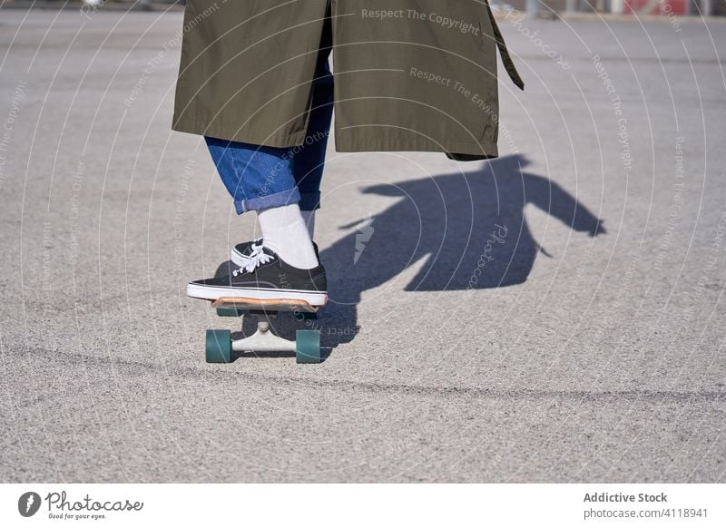 Ein Mann fährt auf einem Skateboard auf der Straße mit seinem Regenmantel und Großstadt Typ Sport Menschen Schlittschuh Beton urban Asphalt Erholung sonnig