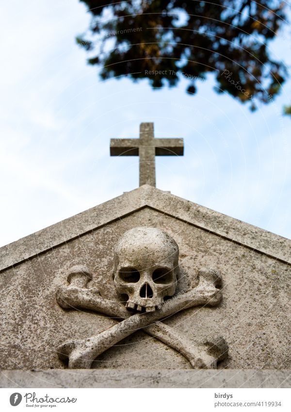 christliches Kreuz mit einem Totenkopf darunter auf einem Friedhof , Froschperspektive Tod sterben Christliches Kreuz Grab Religion & Glaube symbolik