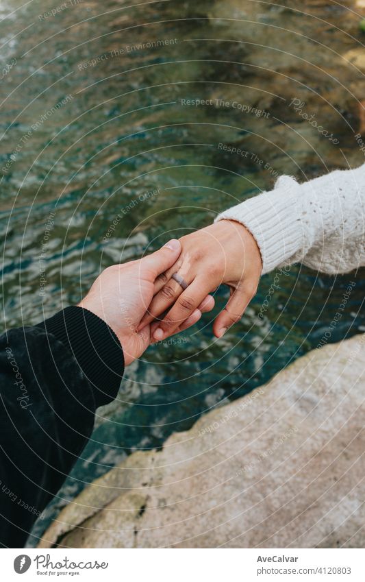 Eine Hand packt eine andere Hand mit einem Fluss als Hintergrund mit einem Gummiring Liebe Konzept Frau Urlaub Mädchen Sommer Strand MEER Ring jung