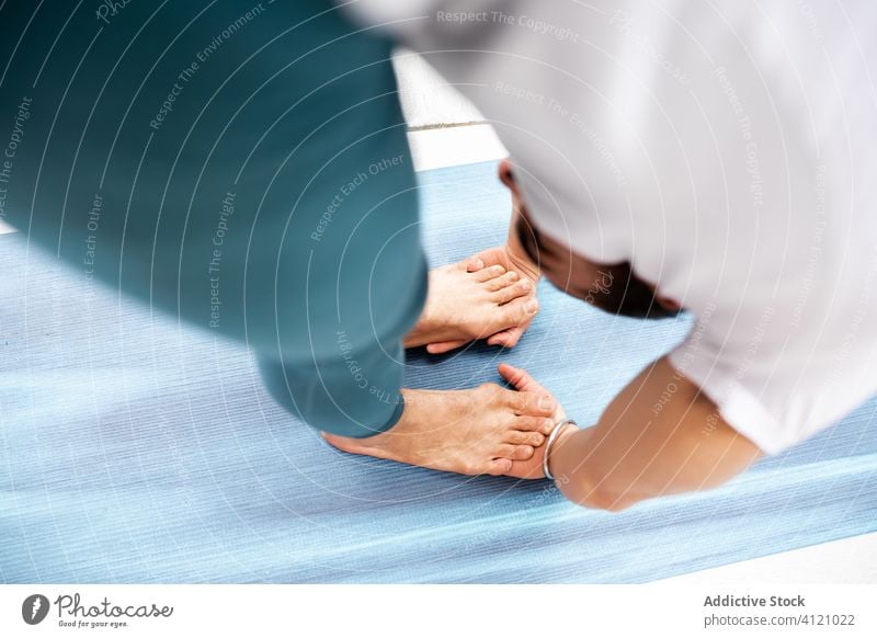 Mann in Gorilla-Pose auf Matte Yoga Übung Training Wegbiegung Unterlage Barfuß modern Dehnung Fitness Form männlich Sportbekleidung Architektur Zeitgenosse Zen