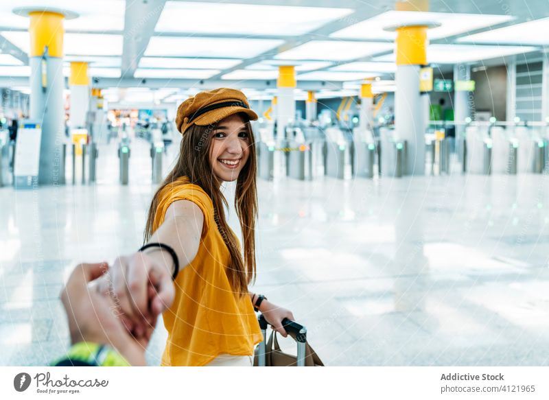 Fröhliche weibliche Reisende hält die Hand ihres Freundes, bevor sie auf Reisen geht Frau Flughafen trendy mir folgen lassen Reisender Abheben gelb