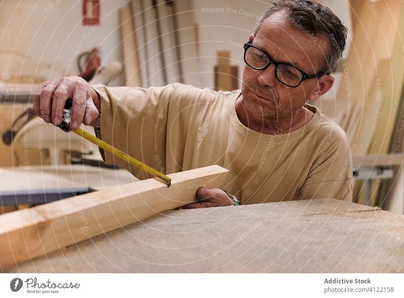 Aufmerksamer Handwerker mit Maßband bei der Arbeit mit Holz in der Tischlerwerkstatt Messung Kunsthandwerker Klebeband Arbeiter Kontrolle Schreinerei achtsam