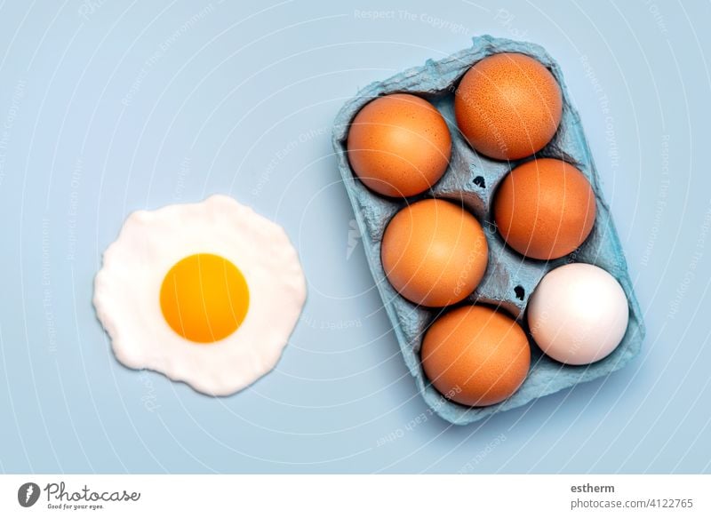 Draufsicht auf Hühnereier in einer offenen blauen Pappschachtel und ein Spiegelei Eier Ostereier Hähnchen frisch Eigelb essen Container Korb Landwirtschaft