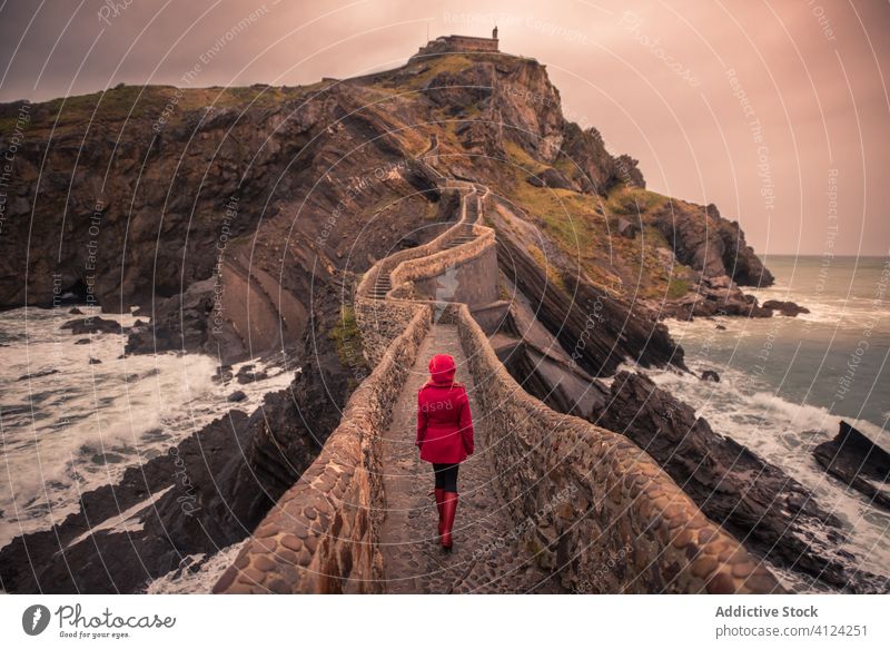Frau, die auf einer steinernen Brücke inmitten des Meeres im Baskenland spazieren geht Tourist Meeresufer Stein Spanien warm reisen erkunden Insel Ausflug Reise