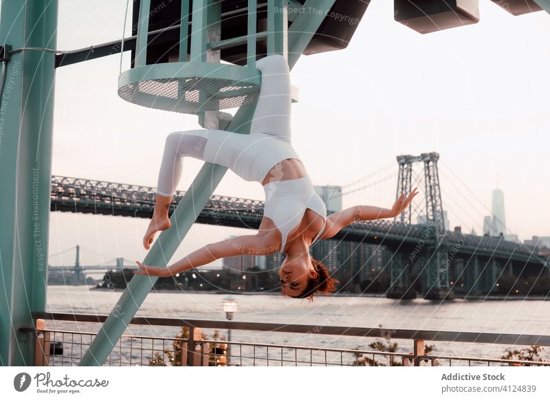 Anmutige Frau hängt kopfüber in der Stadt meditieren Großstadt hängen urban industriell auf den Kopf gestellt ruhig Stadtbild Sportbekleidung Gleichgewicht