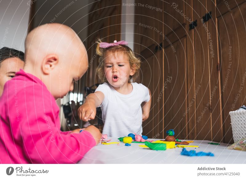 Fröhliche Geschwister, die zu Hause mit Knetmasse spielen Kinder Geschwisterkind Modellierung Ton farbenfroh Mutter Erziehung Entwicklung Vorschule heimwärts