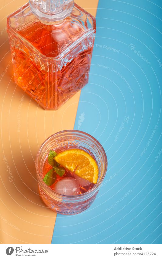 Ein Glas Alkoholcocktail und eine Flasche Rum Cocktail Erfrischung Eis Minze orange kalt Würfel Scheibe Zweig Blatt grün Frucht reif Getränk trinken Kristalle