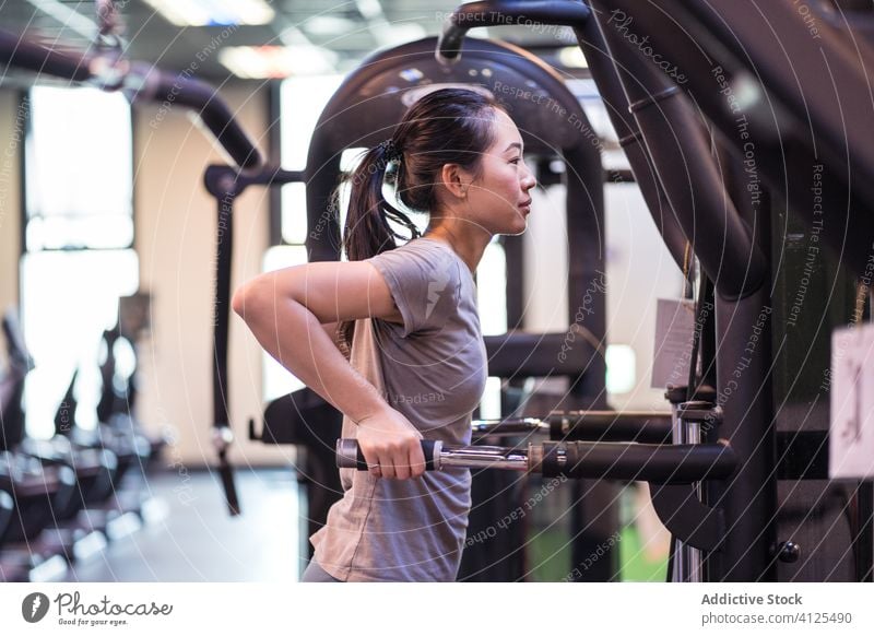Starke ethnische Sportlerin trainiert an einem Trainingsgerät in einem modernen Fitnessstudio Frau Gerät Dip Trizeps Bar Fokus Wohlbefinden Übung Maschine