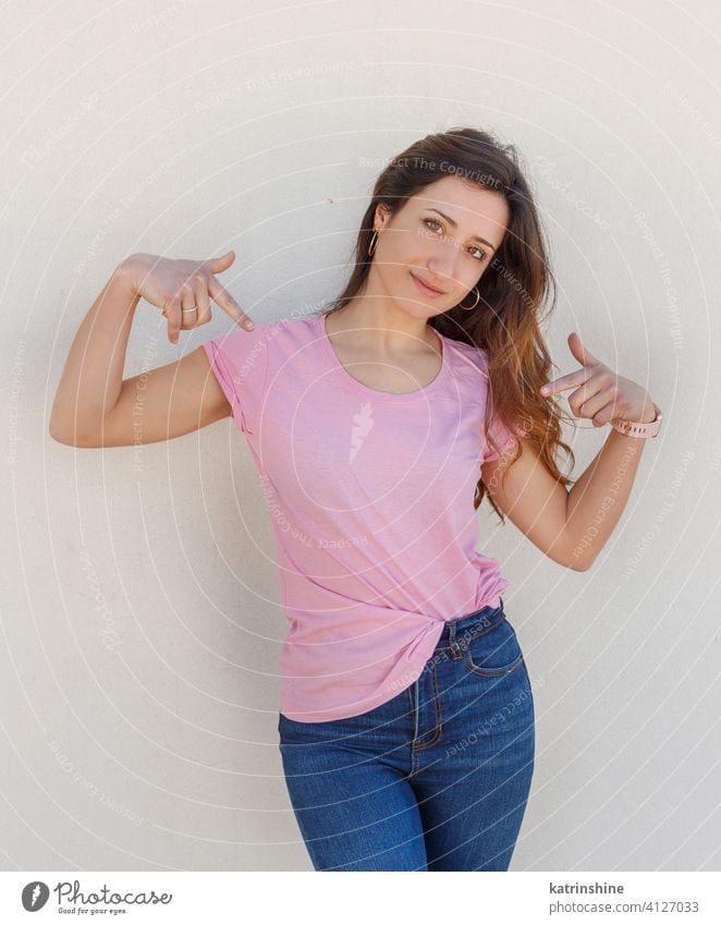 Junge Frauen in T-Shirt und Jeans zeigen auf die Mitte eines T-Shirts jung anhaben Attrappe Jeanshose rosa Punkt Lächeln Rundhals lässig allein schlank