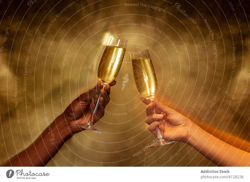Crop multirassischen Paar hält Weingläser mit Champagner auf goldenem Hintergrund Hand Weinglas Party feiern Zuprosten Getränk trinken Alkohol Freund