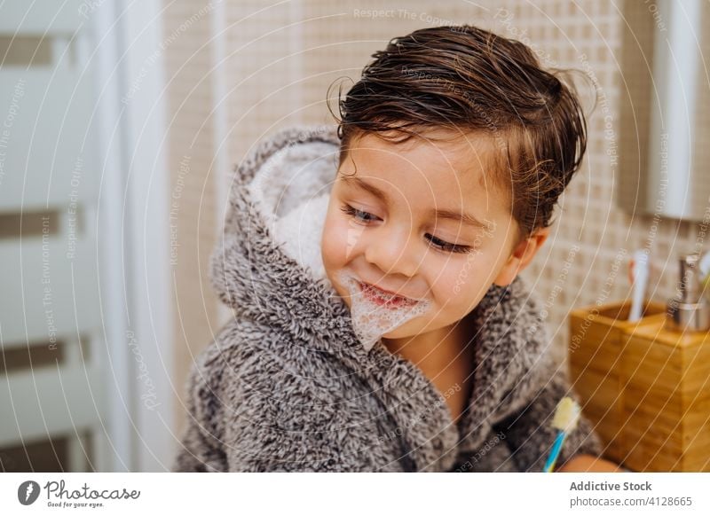 Kleiner Junge beim Zähneputzen im Badezimmer Bürste Zahnbürste wenig Kind Lächeln Bademantel mündlich Hygiene nasses Haar heiter weich gemütlich Komfort