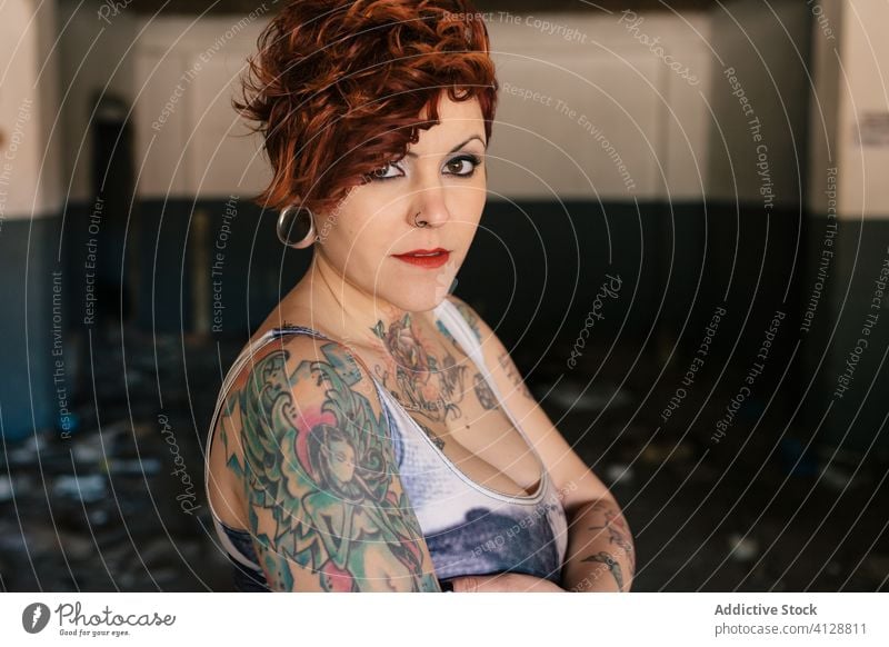 Selbstbewusste tätowierte Frau schaut in die Kamera trendy unabhängig informell Stil alternativ selbstbewusst jung Tattoo Porträt modern Straße kariert schäbig