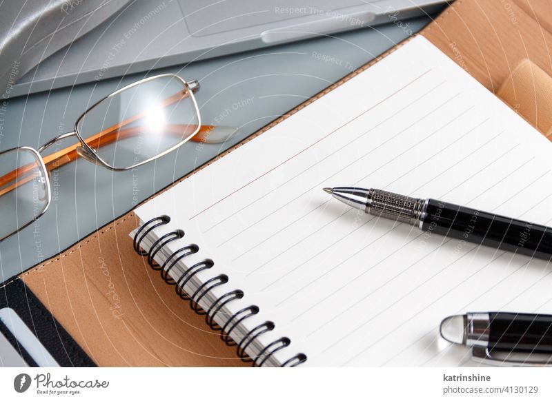 Geöffnete Agenda und Stift auf einer grauen Nahaufnahme Business aufgeklappt schreiben Laptop Planer Schreibstift Büro Schreibtisch abschließen Brille