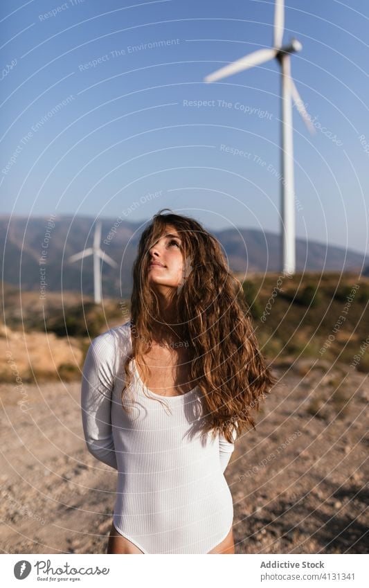 Zarte, allein stehende Frau in der Nähe des Windparks auf sonnigem Feld Landschaft sinnlich Natur Ökologie schlank Stil alternativ Windmühle Energie