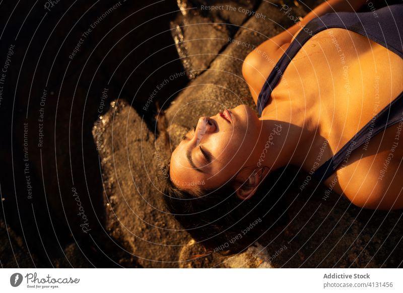 Junge Frau im Badeanzug auf einem Stein am See liegend Ufer Lügen Sonnenuntergang sich[Akk] entspannen felsig Sommer Feiertag Urlaub Windstille Gelassenheit