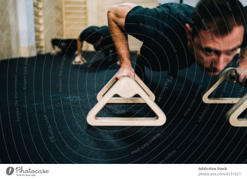 Muskulöse Männer machen Liegestütze am Barren hochschieben Sportler Fitnessstudio Athlet Liegestützstange Menschengruppe intensiv Training stark muskulös