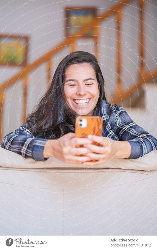 Lächelnde junge Frau mit Smartphone auf dem Sofa heimwärts benutzend Glück Selfie Browsen lässig Apparatur online Lügen Internet gemütlich Gerät