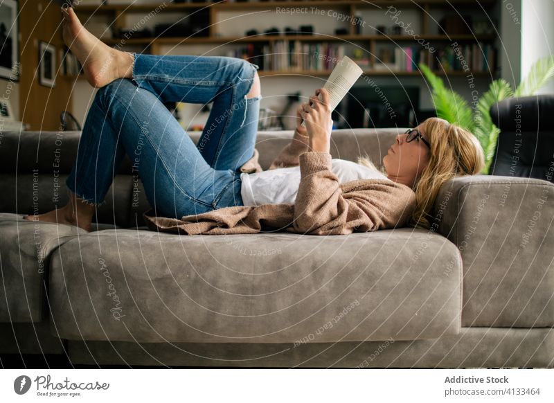 Nachdenkliche Frau liest ein Buch im Wohnzimmer lesen sich[Akk] entspannen heimwärts nachdenklich besinnlich interessant Lügen Sofa klug Roman Wochenende