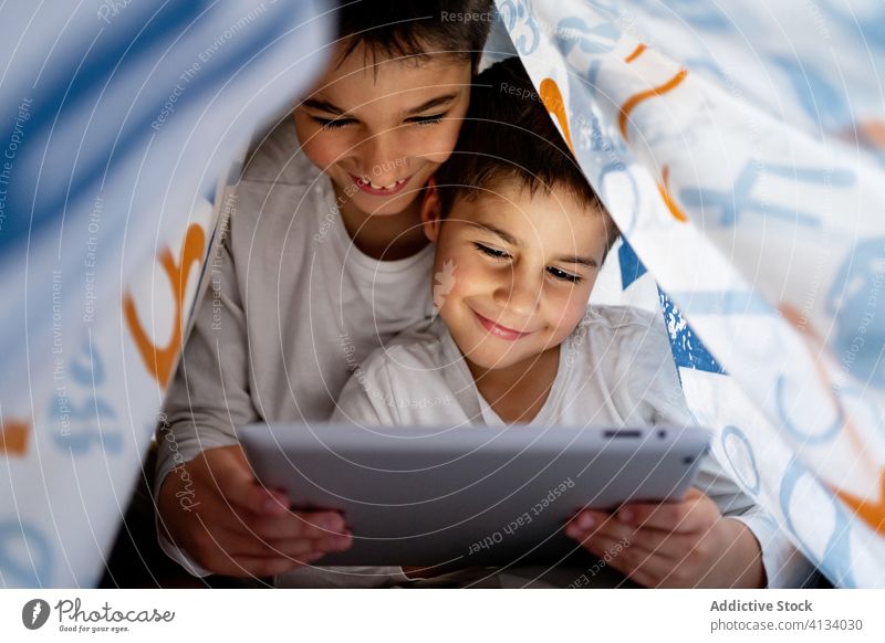 Glückliche Brüder sehen sich gemeinsam ein Video auf einem Tablet an zuschauen Karikatur Zusammensein Tablette Bruder Geschwisterkind Browsen Pyjama Decke