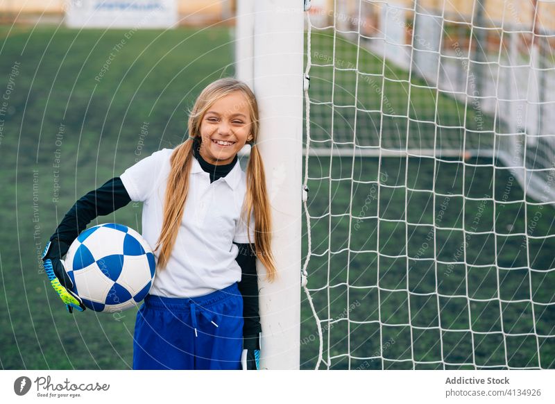 Glückliche junge Spielerin mit Ball in Fussballarena im Sportstadion Mädchen Fußball Feld Uniform Kind Club Kindheit Athlet Gerät Lächeln Schulmädchen heiter