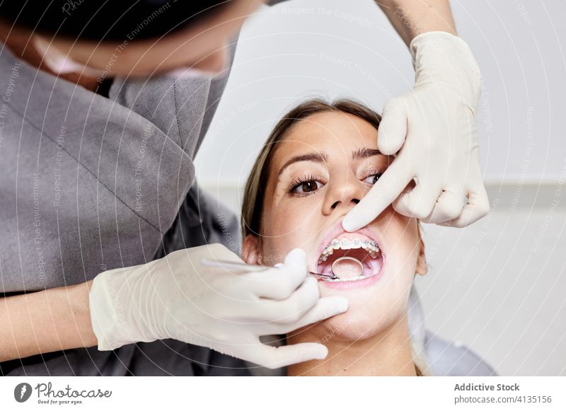 Zahnarzt prüft Zähne des Patienten Frauen geduldig untersuchen Klinik Spiegel Klammer Handschuh Mund geöffnet Arbeit professionell prüfen Zeitgenosse mündlich