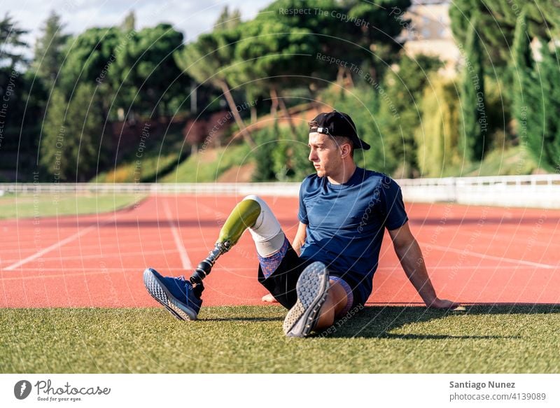 Behinderter Mann Athleten ausruhen Porträt Vorderansicht aussruhen Sitzen Stadion Laufbahn Läufer Sport Prothesen Prothetik Behinderung deaktiviert paralympisch