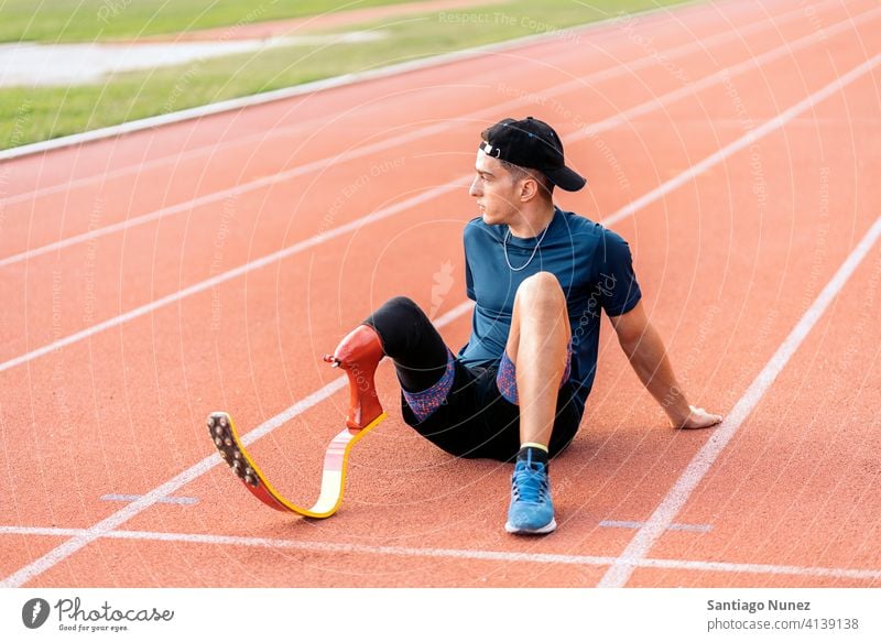 Behinderter Mann Athleten ausruhen Porträt Vorderansicht aussruhen Sitzen Stadion Laufbahn Läufer Sport Prothesen Prothetik Behinderung deaktiviert paralympisch