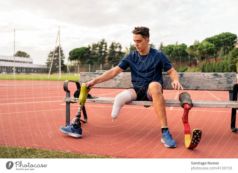 Behinderter Mann Sportler sitzt auf einer Bank Setzen sich[Akk] ändernd Beinprothese Sitzen Porträt Junge Laufbahn Stadion Athlet jung Läufer Prothesen