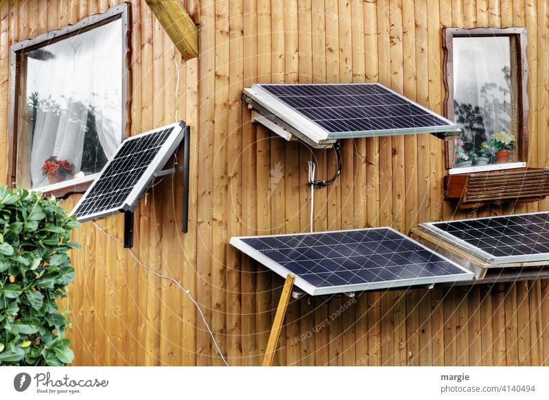 Kleingartenidylle: Solarpaneele am Gartenhaus schrebergarten menschenleer pflanze Hecke Paneele Holzhaus Fensterrahmen Blumentopf Solarenergie Solarmodul