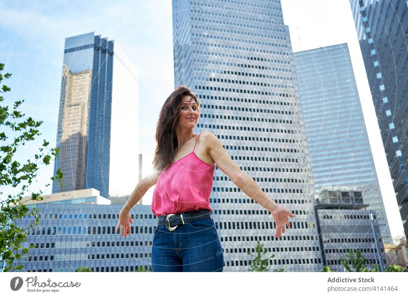 Entschlossene lächelnde Geschäftsfrau gegen Wolkenkratzer in der Innenstadt Stadtzentrum Bestimmen Sie professionell selbstbewusst Großstadt Unternehmer