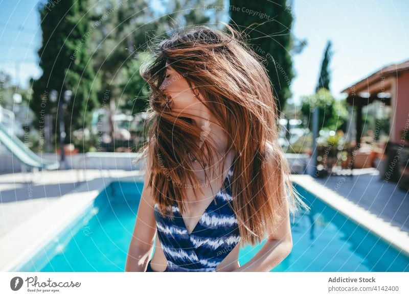 Zufriedene Frau im Badeanzug am Pool fliegendes Haar Sommer Urlaub sorgenfrei Beckenrand Badebekleidung Inhalt sonnig sich[Akk] entspannen ruhen Feiertag heiter