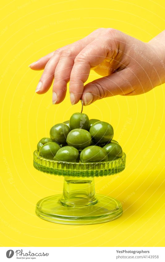 Frau nimmt eine grüne Olive in die Hand. Essen frische Bio-Oliven olea europaea Amuse-Gueule Hintergrund Nahaufnahme Farbe farbenfroh Textfreiraum Küche