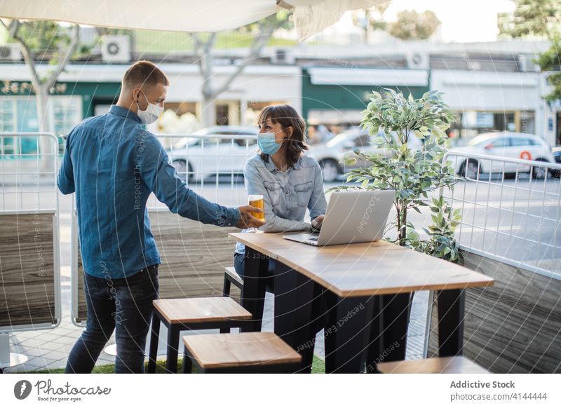Frau arbeitet am Laptop in einem Straßencafé und wartet auf eine Bestellung Menschen dienen Bier frisch Café Kellner Klient freiberuflich Arbeit Coronavirus