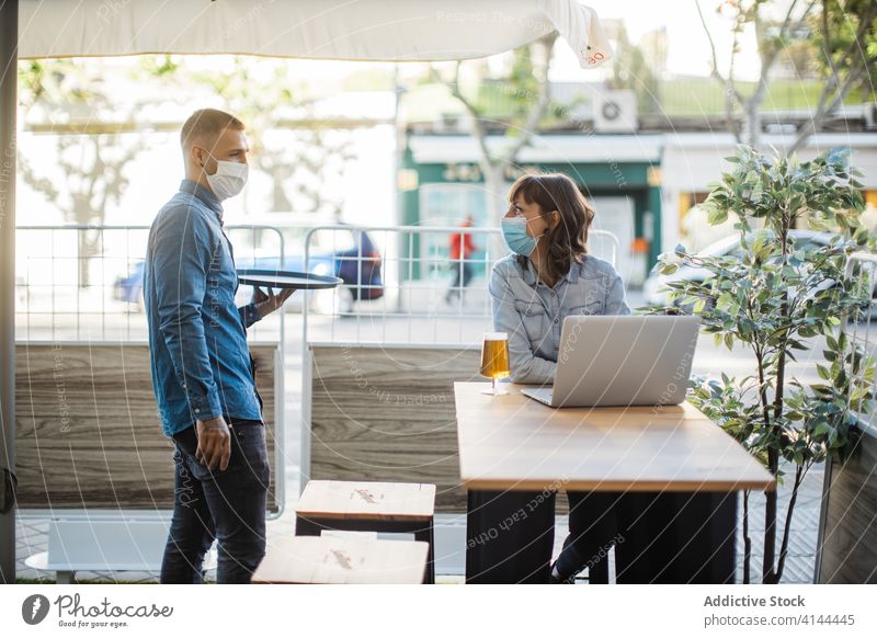 Frau arbeitet am Laptop in einem Straßencafé und wartet auf eine Bestellung Menschen dienen Bier frisch Café Kellner Klient freiberuflich Arbeit Coronavirus
