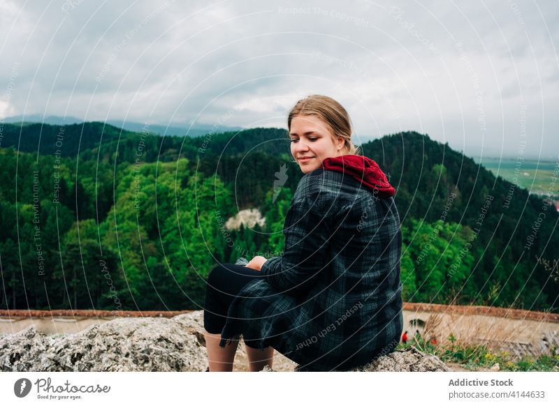 Unbekümmerte Frau, die sich auf einem hohen Aussichtspunkt vor malerischen Grashügeln ausruht Reisender majestätisch Hochland Hügel Landschaft erstaunlich