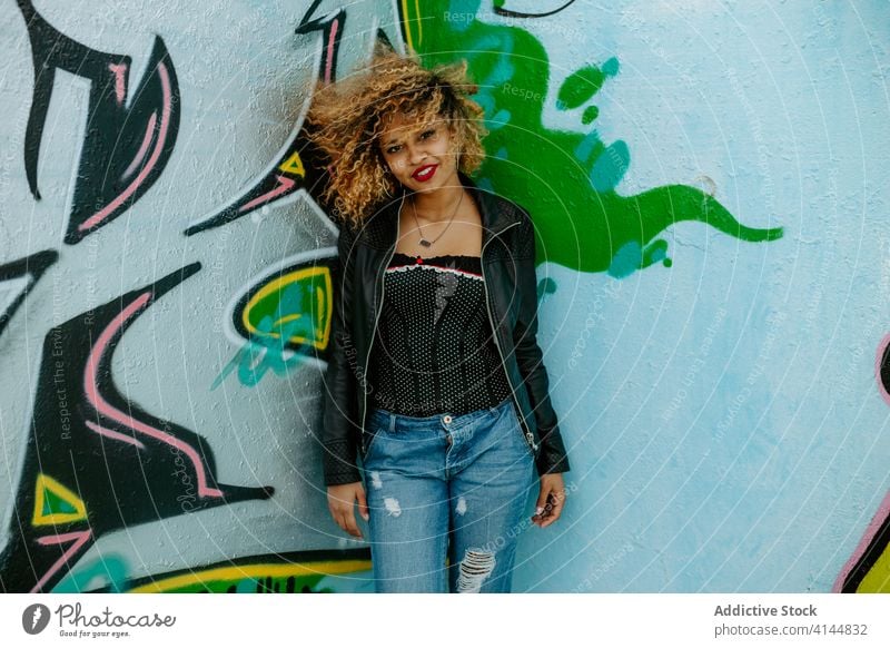 Junge lächelnde Frau in der Nähe einer Graffiti-Wand Stil tausendjährig kreativ Großstadt urban trendy Lächeln positiv ethnisch schwarz Afroamerikaner jung