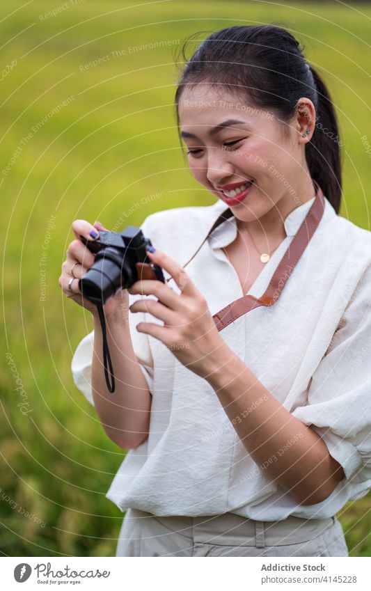 Lächelnde ethnische Frau fotografiert auf einem Feld fotografieren altehrwürdig Fotoapparat Natur Reis Moment Gedächtnis asiatisch Sommer Fotografie Urlaub jung