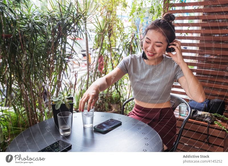Asiatische Frau sieht Video auf Smartphone zuschauen lustig Kopfhörer genießen unterhalten benutzend Lächeln asiatisch ethnisch Sommer Apparatur jung Gerät