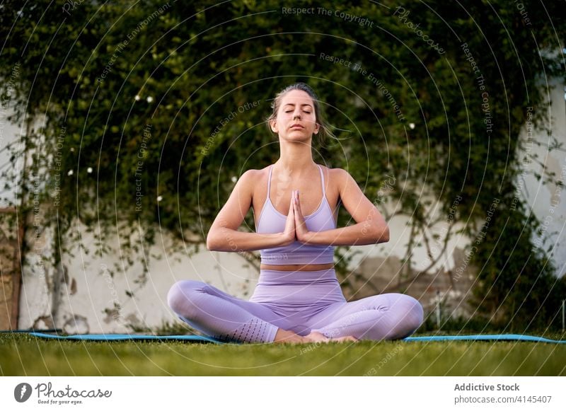 Frau meditiert in Lotus-Pose im Innenhof meditieren Yoga friedlich Asana padmasana Namaste gestikulieren ruhig aktive Kleidung Windstille Zen