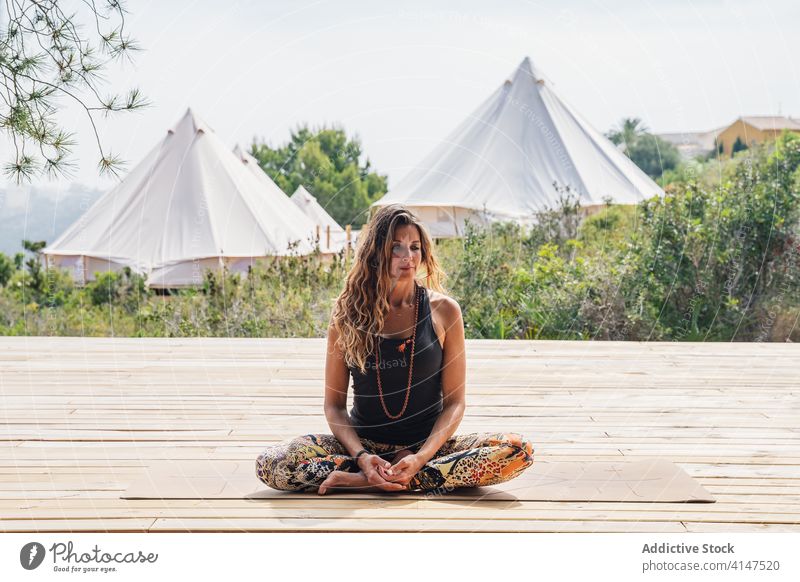 Ruhige Frau in entspannender Ardha Padmasana Yogastellung üben halber Lotus ardha padmasana Lager Harmonie friedlich Windstille Gesundheit Asana ruhig tropisch
