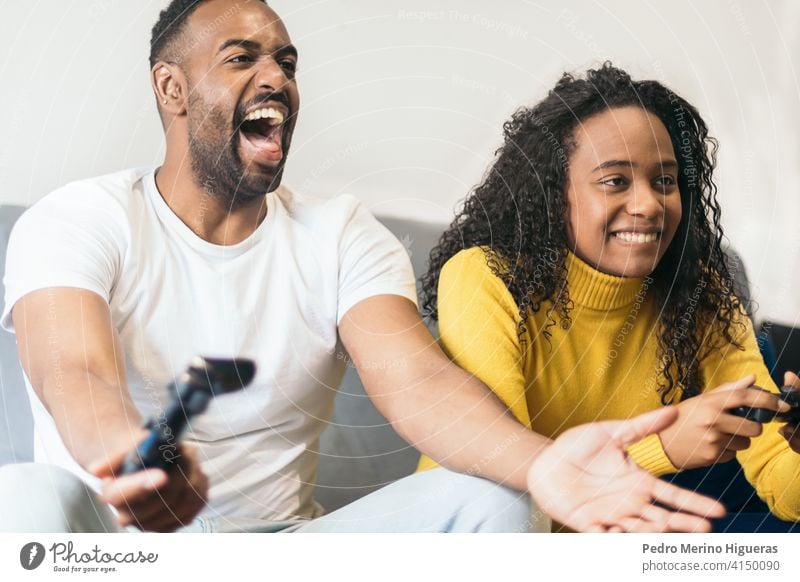 Schwarzes Paar, das mit Begeisterung zu Hause ein Videospiel spielt. schwarz heimwärts Frau Konsole männlich Spaß Spiel Menschen Glück Spieler Spielen Mann