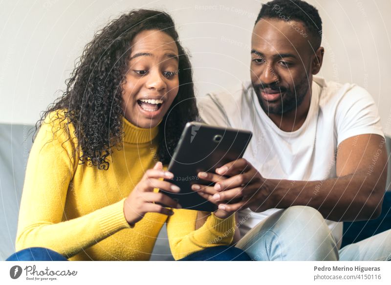 afroamerikanisches Paar, das Tablet zu Hause beobachtet Mann heimwärts Frau Internet schwarz Menschen Glück Technik & Technologie Tablette Lächeln jung