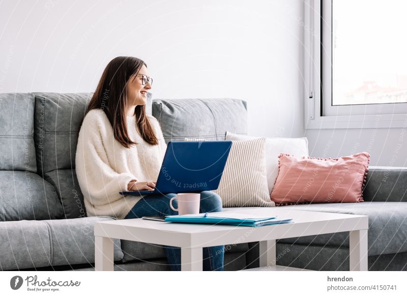 Frau mit Laptop auf ihrem Sofa zu Hause im Innenbereich benutzend arbeiten Arbeit Büro Gespräch Job Notebook jung Glück Tippen lernen Nur eine Frau Unternehmer