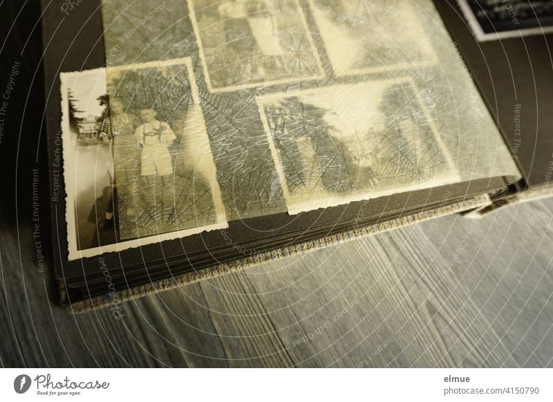 Blick in ein altes Fotoalbum mit schwarz-weiß Fotografien und Pergamentpapier zwischen den schwarzen Seiten / analoge Fotografie / Demenztherapie Papierbild
